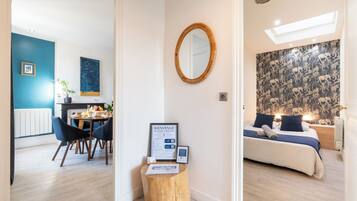 Een hotelkamer met een bed, een spiegel, een klein houten krukje en een welkomstbord.