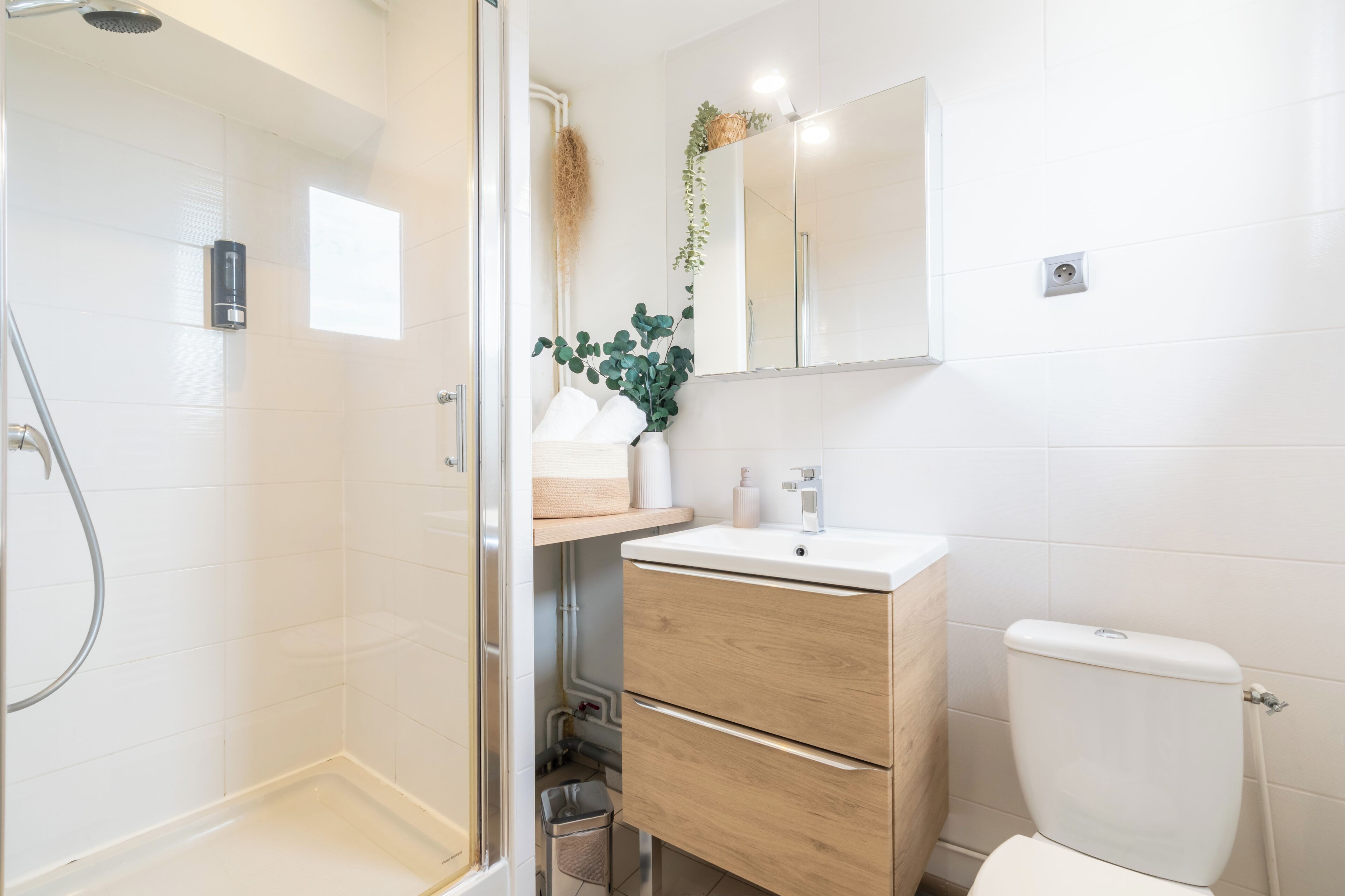 Een moderne badkamer met een douchecabine van glas, een houten wastafelmeubel met een wastafel en een toilet.