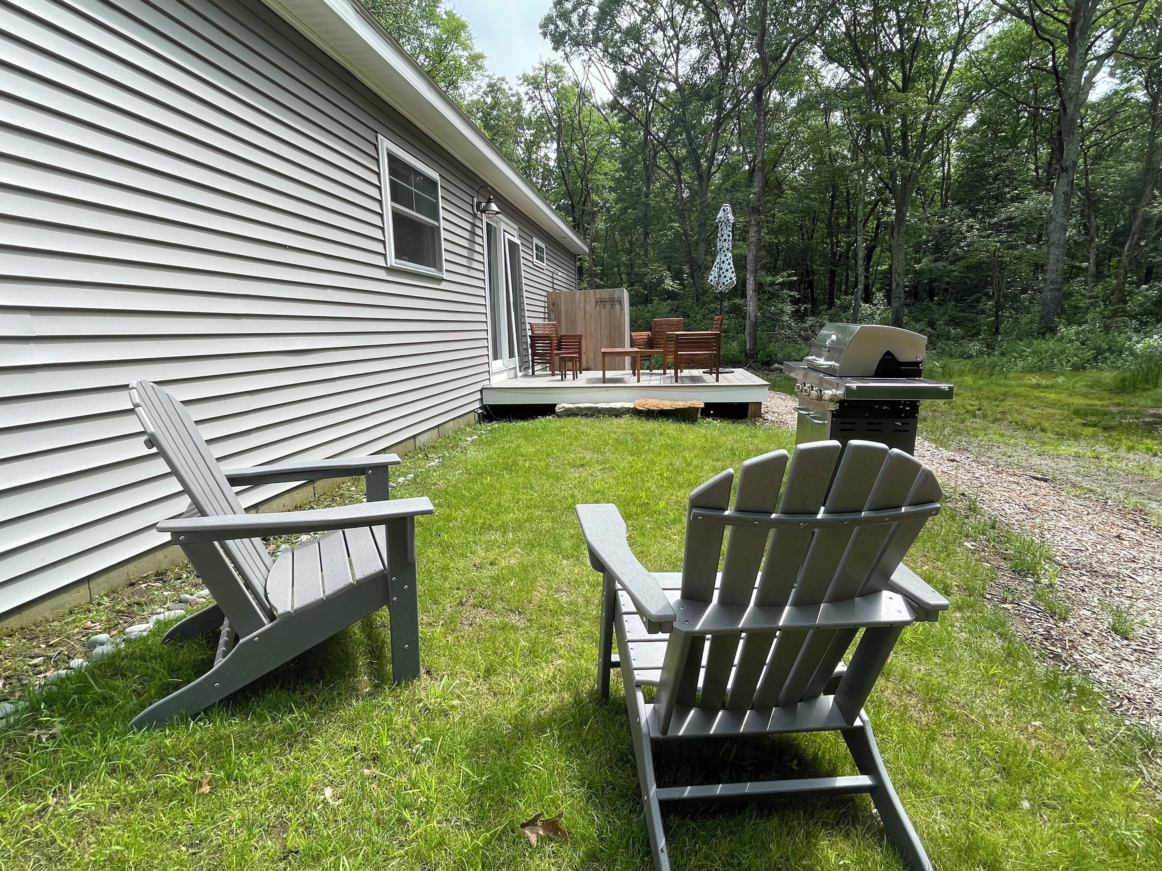 A house with a deck, outdoor seating, and a grill.