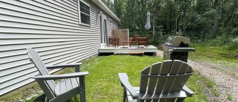 A house with a deck, outdoor seating, and a grill.