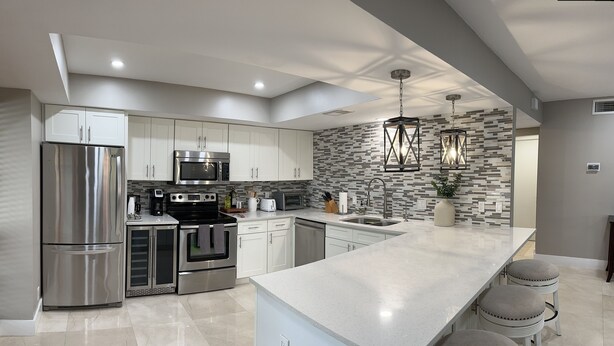 A modern kitchen with stainless steel appliances, a large island, and a unique patterned backsplash.