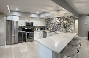 A modern kitchen with stainless steel appliances, a large island, and a unique patterned backsplash. - PGA National golf villa condo , 2 bed, 2 bath. PRIME LOCATION. (Palm Beach Gardens)