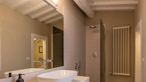Une salle de bain moderne avec un grand lavabo blanc, un miroir et un espace douche.