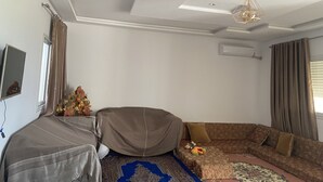 A living room with a sofa, a small table, a decorative plant, and a ceiling light fixture. - Built in 2024, Sea view (sousse)