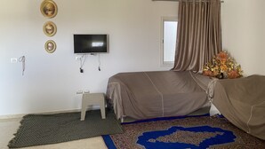 A bedroom with a bed, a television, a small stool, a window with curtains, and a decorative vase. - Built in 2024, Sea view (sousse)