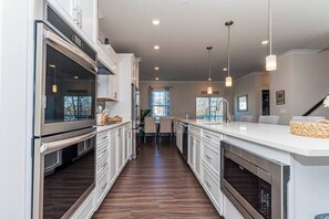 A modern kitchen with white cabinetry, stainless steel appliances, and pendant lighting. - Luxury Townhome WestOC -4 BRS / golf / asssateague (Berlin)