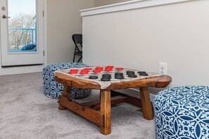 A room with a wooden table for board games, a chair, and a patterned ottoman. - Luxury Townhome WestOC -4 BRS / golf / asssateague (Berlin)