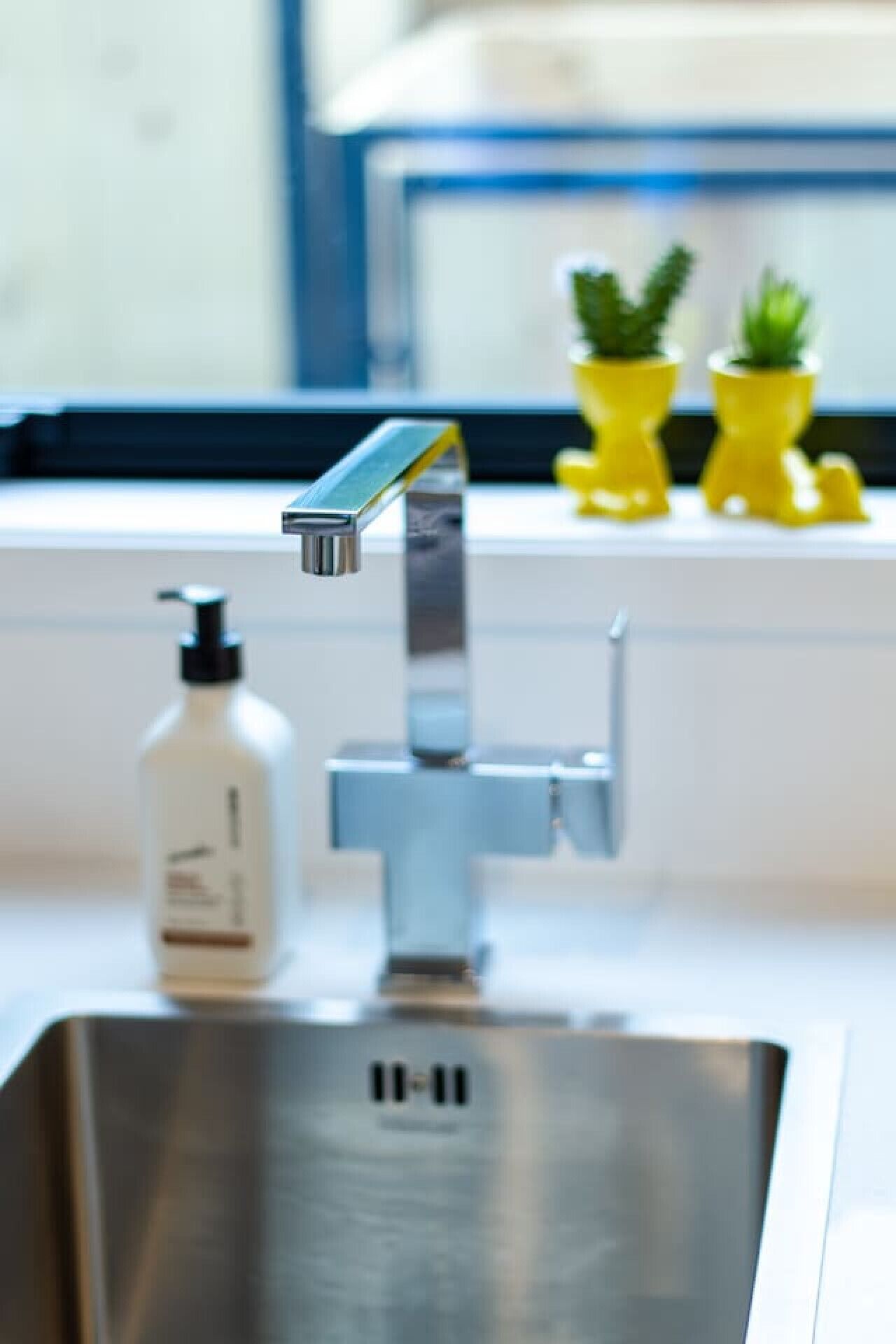 A modern kitchen with a stainless steel sink, a faucet, and a bottle of hand soap.