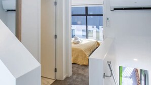 Een modern interieur met een bekleed trappenhuis dat leidt naar een slaapkamer met een groot raam.