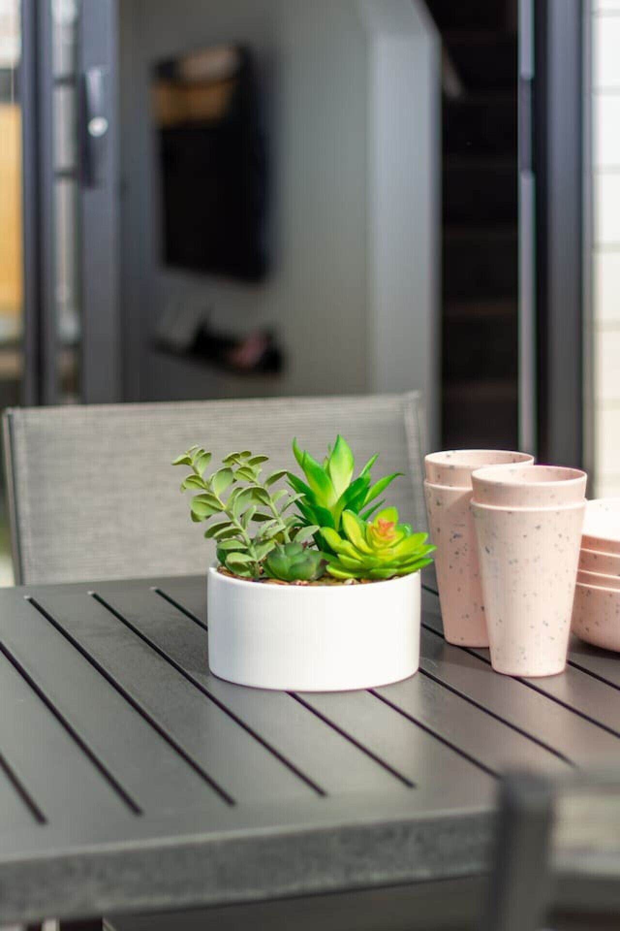 A table with a potted plant and several pink cups.