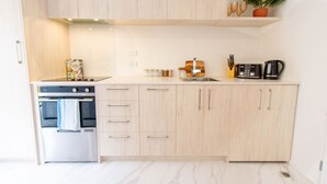 A modern kitchen with light wood cabinets, a built-in oven, and a coffee maker on the countertop.