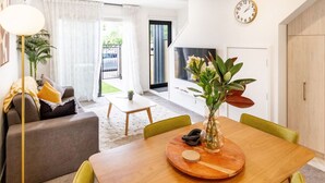 Un salon moderne avec une table à manger en bois, des chaises vertes, un canapé et un lampadaire.