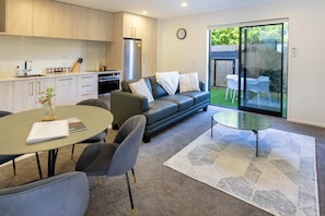 A modern living room with a sofa, a coffee table, and a dining area with a table and chairs.