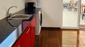 Una cucina compatta con lavandino, macchina per caffè e dispenser d'acqua.