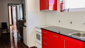 Una cucina con mobili rossi, un piano cottura bianco e un ripiano nero.