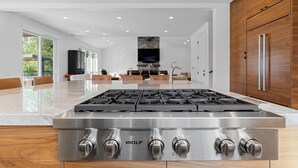 A modern kitchen with a large gas stove, wooden cabinets, and a central island. - Healdsburg Modern home, 3BR/3.5BA pool, hot tub, outdoor kitchen, WiFi (Healdsburg)