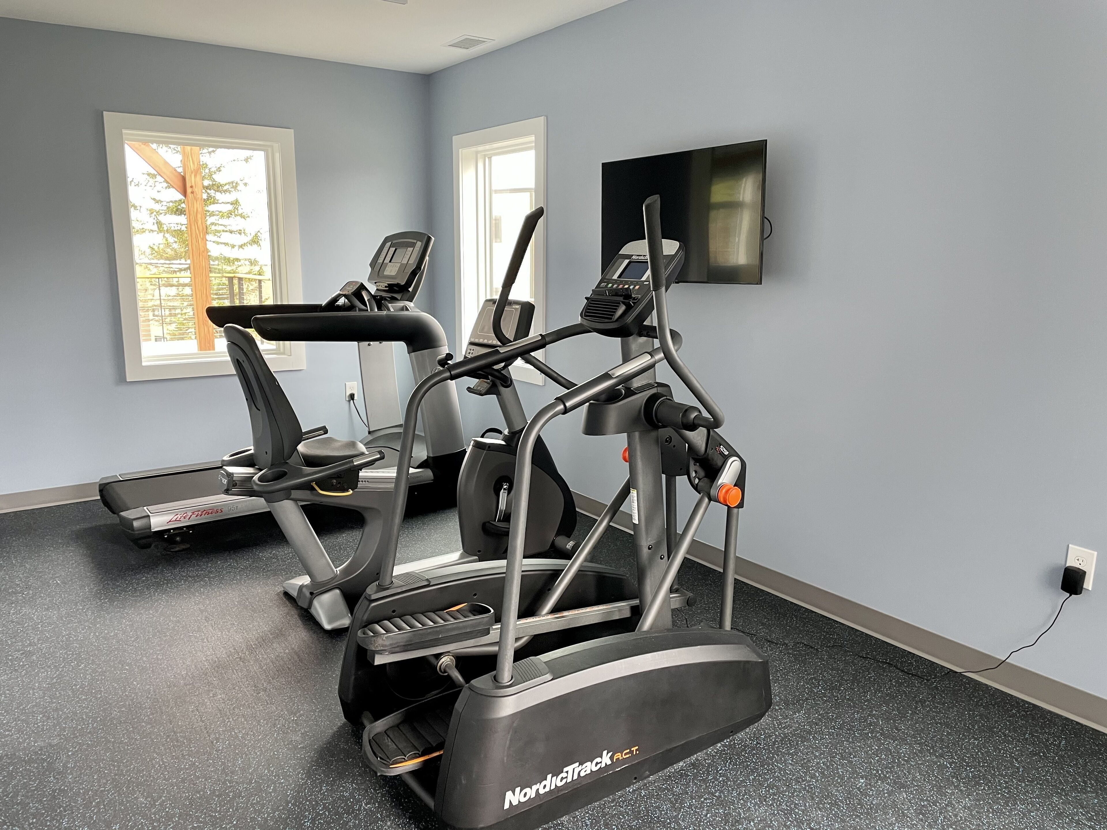 Une salle de sport équipée de tapis de course, d’un vélo elliptique et d’un vélo d’appartement.