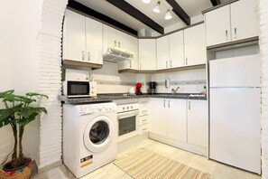 A compact kitchen with white cabinets, a microwave, a washing machine, and a refrigerator. - Calahonda 2BED apartment - great location (Mijas Costa)