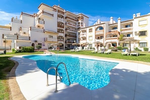 Un hotel con piscina, varios balcones y un césped cuidado.