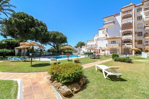 A hotel courtyard with a swimming pool, lounge chairs, and a well-maintained lawn.