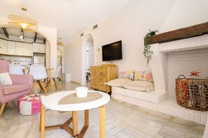 A living room with a white sofa, a round table, and a TV mounted on the wall.