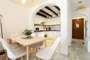 Een moderne keuken met witte kasten, een houten eettafel en witte stoelen.