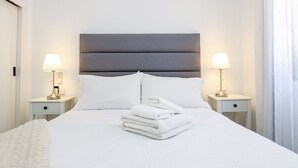A neatly made bed with white linens and towels, two bedside lamps, and a grey headboard. - Calahonda 2BED apartment - great location (Mijas Costa)