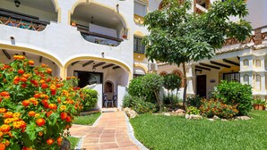 A courtyard with a paved pathway, surrounded by lush greenery and flowering plants. - Calahonda 2BED apartment - great location (Mijas Costa)