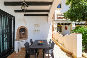 Un patio con una mesa y sillas, un horno de ladrillo y una lámpara colgante.