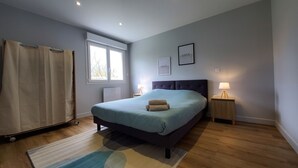 Een slaapkamer met een bed, twee nachtkastjes, een raam en een gordijn.