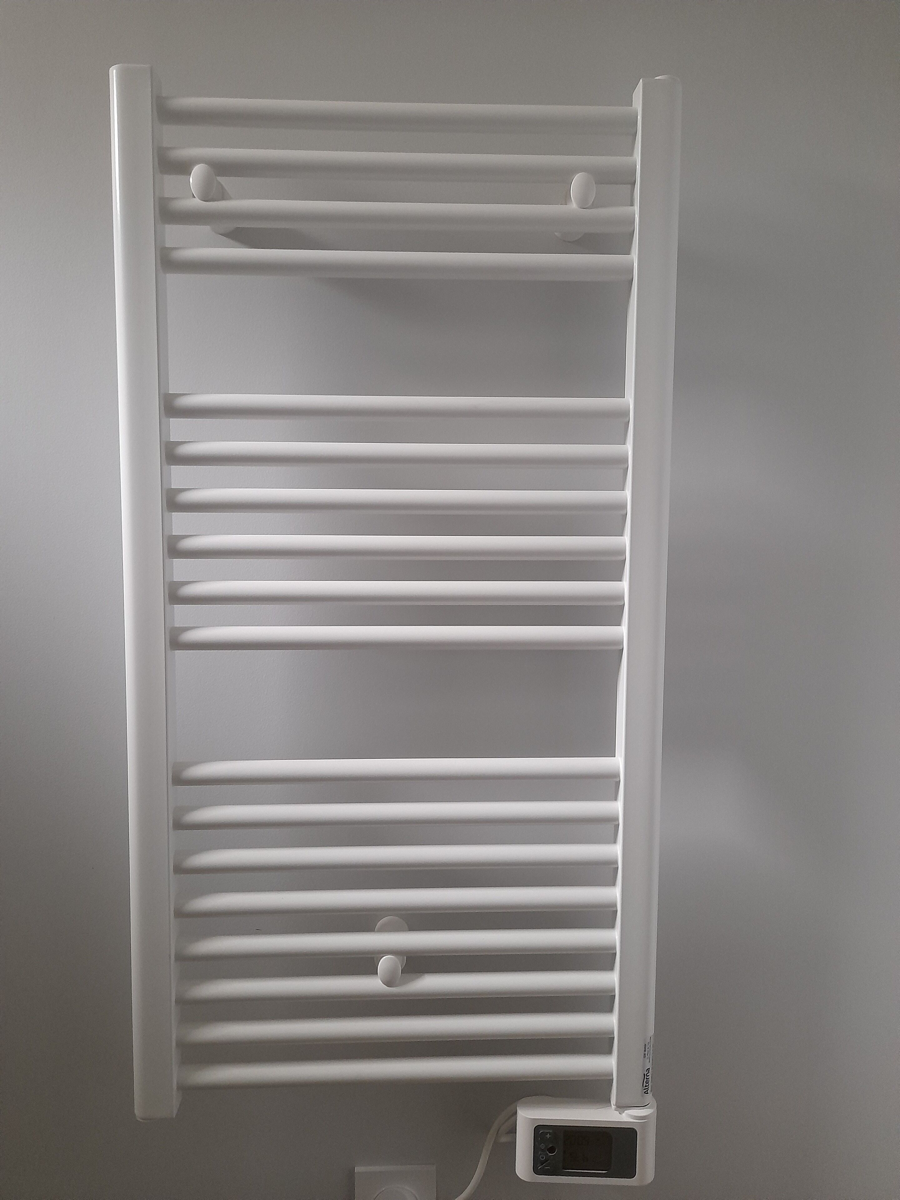 A white radiator with horizontal slats and a digital control panel below it.