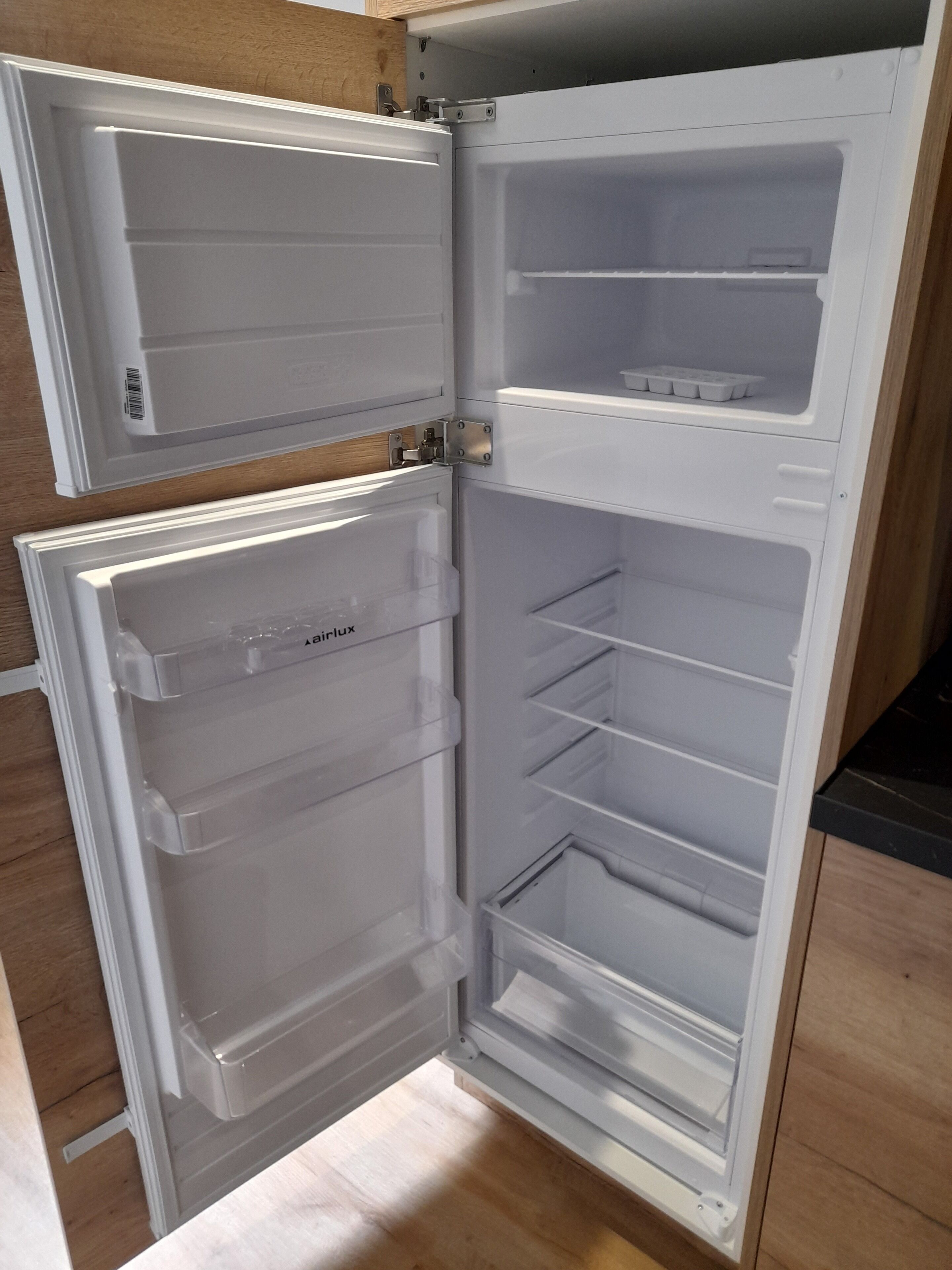 Un refrigerador blanco con dos puertas, un compartimento congelador y varios estantes.