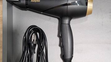 A black and gold hair dryer with a cord, placed in a drawer.