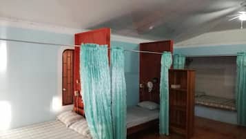 A room with a bed, a small table, and a shelf.
