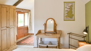 A bedroom with a wooden wardrobe, a mirror, a bedside table with a lamp, and a map on the wall. - 1 bedroom accommodation in Newton-on-the-Moor (Newton-on-the-Moor)