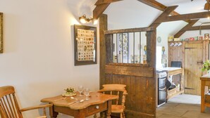 A rustic dining area with wooden furniture, a framed collection of vintage coins, and a kitchen visible through an open door. - 1 bedroom accommodation in Newton-on-the-Moor (Newton-on-the-Moor)