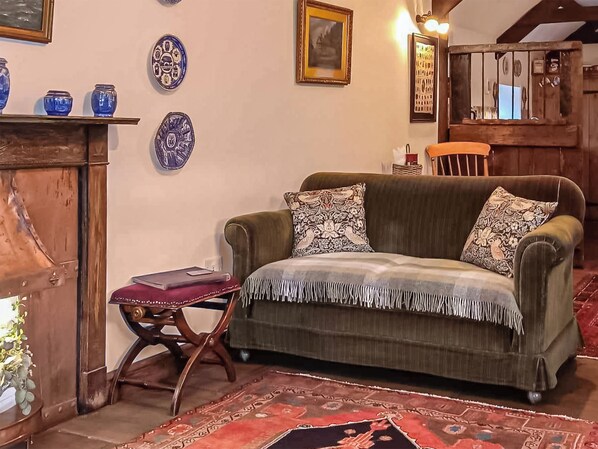 A cozy living room with a green sofa, patterned cushions, a wooden side table, and a decorative rug. - 1 bedroom accommodation in Newton-on-the-Moor (Newton-on-the-Moor)