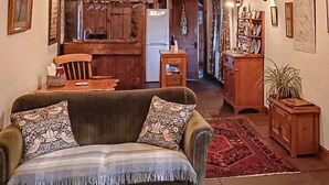 A cozy living room with a sofa, patterned cushions, and a red rug. A wooden dining table with chairs is visible in the background. - 1 bedroom accommodation in Newton-on-the-Moor (Newton-on-the-Moor)