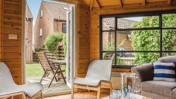 A wooden interior with a sliding glass door leading to a patio, a sofa, two chairs, and a tray with glasses and a pitcher. - 5 bedroom accommodation in Runswick Bay, near Whitby (Runswick Bay, near Whitby)