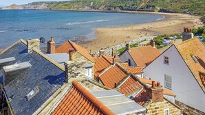 A coastal town with terracotta-roofed buildings, a sandy beach, and a view of the sea. - 5 bedroom accommodation in Runswick Bay, near Whitby (Runswick Bay, near Whitby)