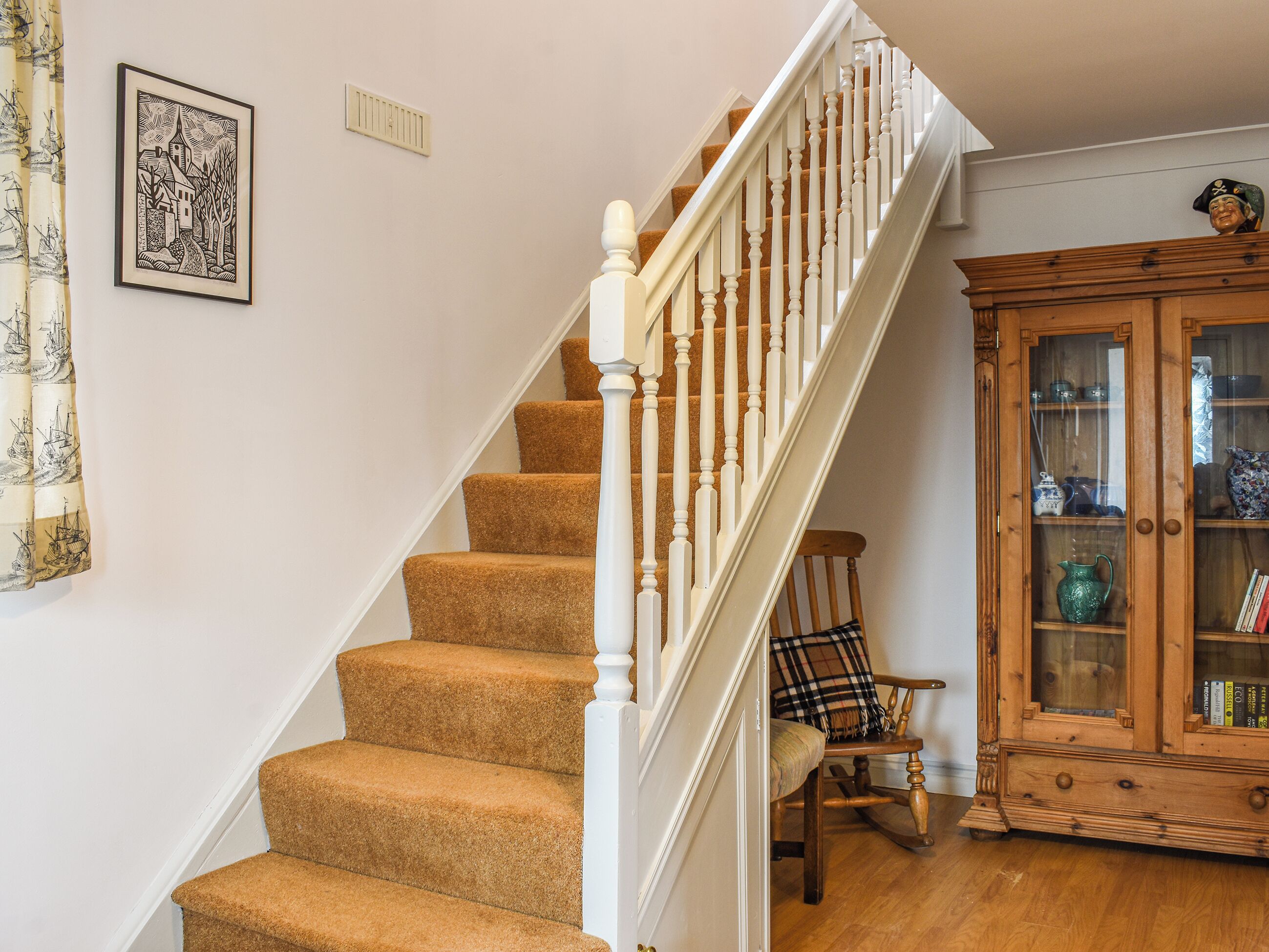 Un escalier avec une rampe blanche et des marches recouvertes de moquette.