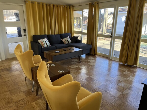 Un salon moderne avec un canapé, deux fauteuils jaunes, une table basse et une vue dégagée grâce à de grandes fenêtres.
