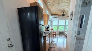 Una cocina con un refrigerador negro, armarios de madera y techo de madera.