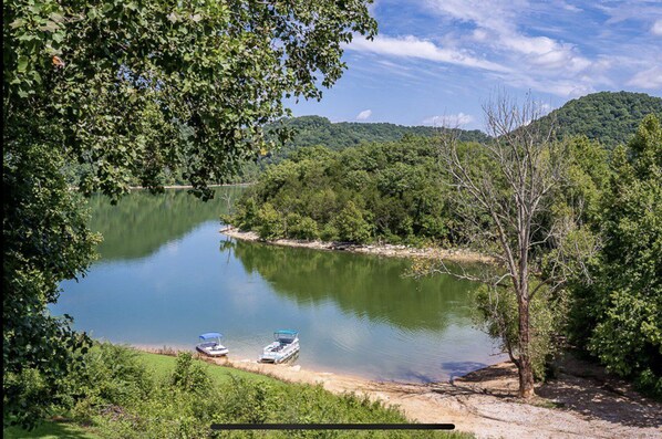 A calm lake surrounded by dense greenery and hills. Two boats are docked at the shore. - Tiny House on Center Hill Lake (Baxter)