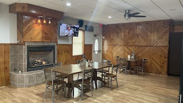 Enjoy meals in this cozy dining area with a fireplace, wooden dining table, and television.