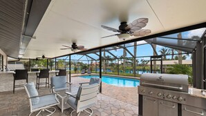Une terrasse extérieure avec une piscine, un barbecue et des sièges.