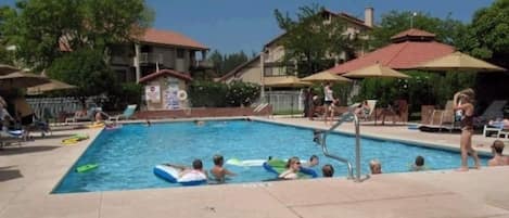 Relax by the pool surrounded by lush greenery and comfortable lounge chairs.