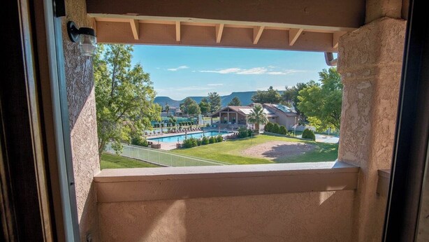 Ein Balkon mit Blick auf ein Schwimmbecken, ein Haus und ein Gebirge.