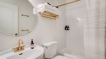 A bathroom with a white sink, a toilet, a bathtub, and a shower curtain.