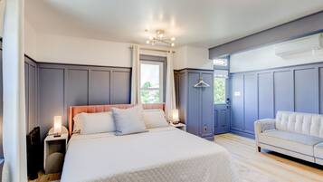 Un dormitorio con una cama grande, mesitas de noche, un sofá y un armario.